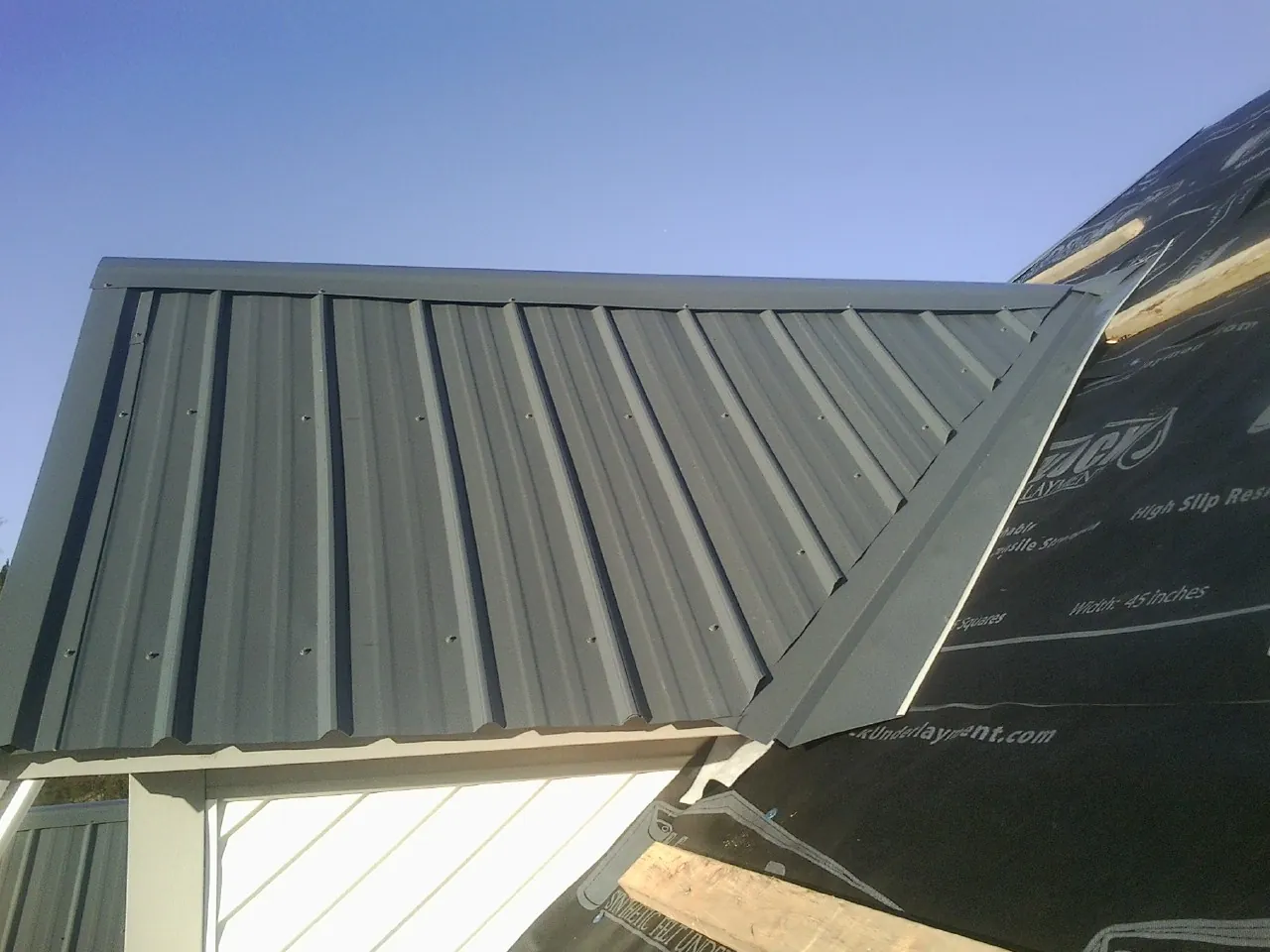 Gray metal roof panels going on over a garage gable in Parkhill