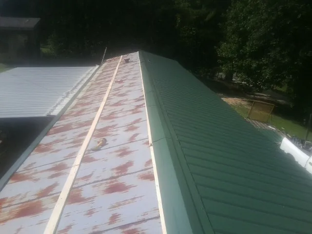 Old rusted panels beside newly installed green metal roofing — Wind Damage Roof Repair by Roofing Brothers in Parkhill