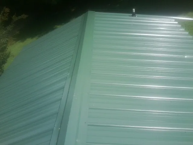 New green metal panels meeting at the ridge of a roof — Flat Roof Repair work by our crew in Parkhill