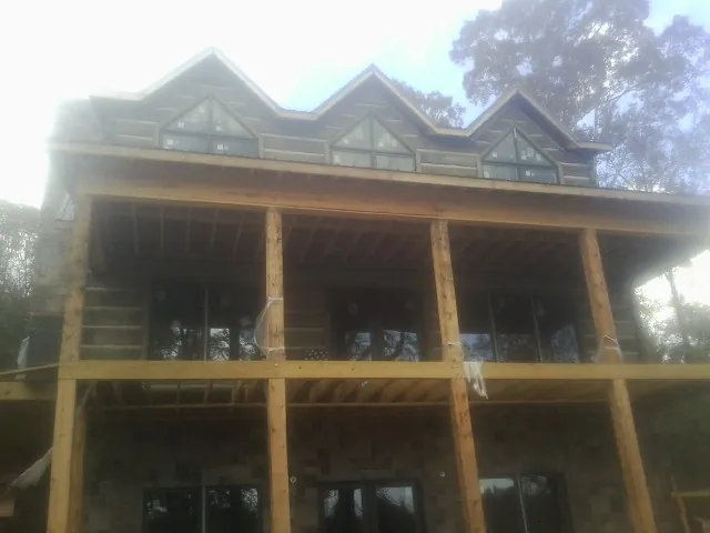 Dormers and porch framing on a large log home under construction — Roof Coating work by our crew in Parkhill