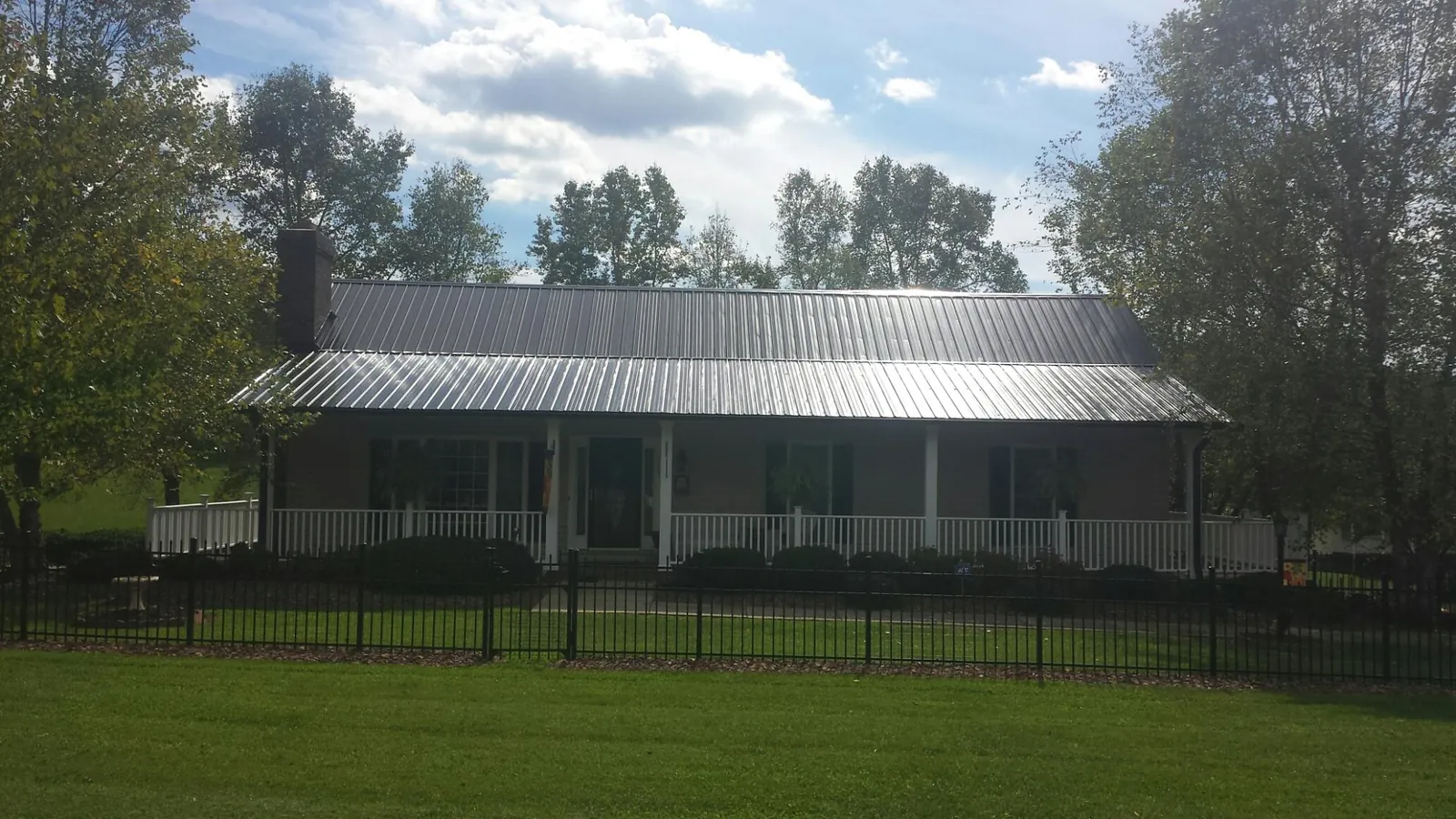 Gray metal roof on a brick ranch with a full width front porch — Gutter Guard Installation work by our crew in Parkhill