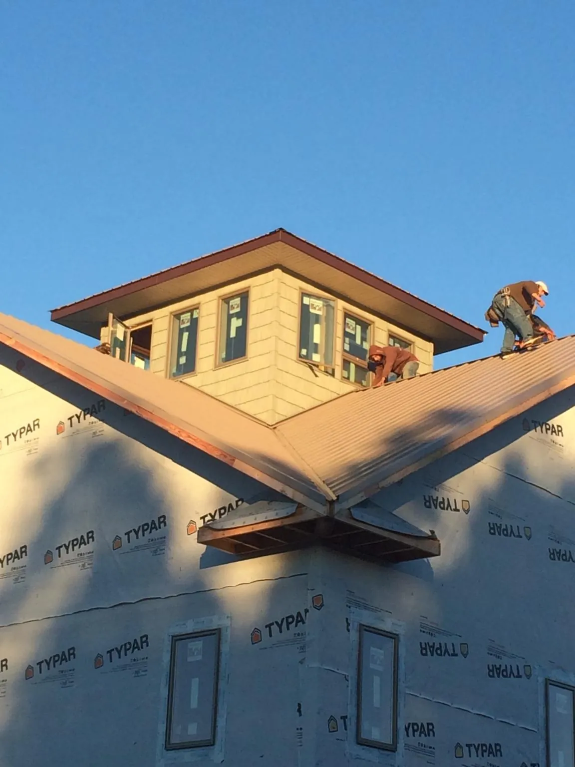 Roofers working around a rooftop cupola on a new metal roof at sunset — Roof Waterproofing in Parkhill by Roofing Brothers